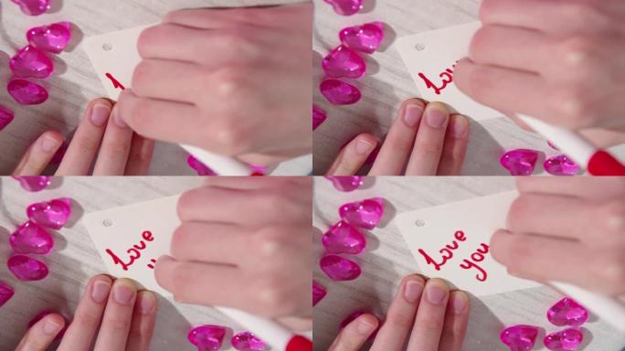 手写文字爱你，用红色记号笔在桌子上的纸上画心形。自制情人节贺卡。DIY礼品概念。爱情概念