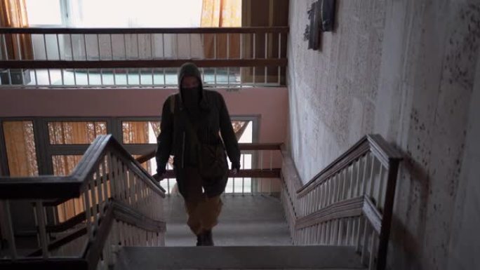 戴着防毒面具的跟踪者走在废弃的建筑里，特写镜头。后启示录和核冬天