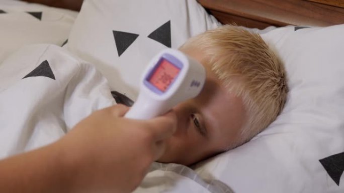 一位母亲用红外温度计测量生病男孩的温度。