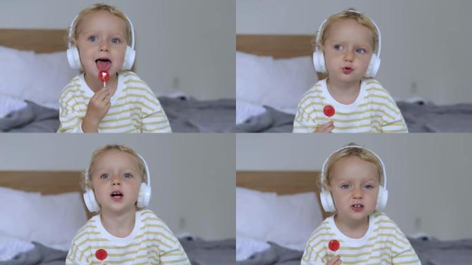 一个3岁的婴儿坐在床上，嘴里放着红色的甜糖，带有浆果的味道。她环顾四周，跟着耳机里的一首歌一起唱歌。