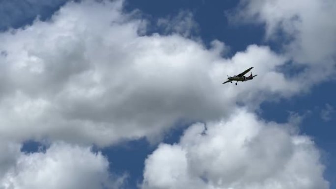 轻型飞机在布满蓬松云彩的明亮天空下降落的途中头顶