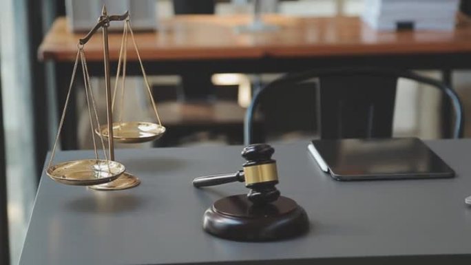 正义与法律概念。法庭上的男法官带着木槌，与计算机和对接键盘，眼镜一起工作，在晨光下的桌子上