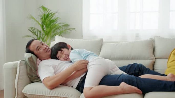 亚洲家庭关系，男孩拥抱父亲并睡在沙发上