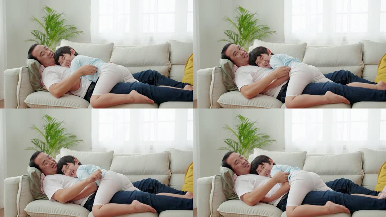 亚洲家庭关系，男孩拥抱父亲并睡在沙发上