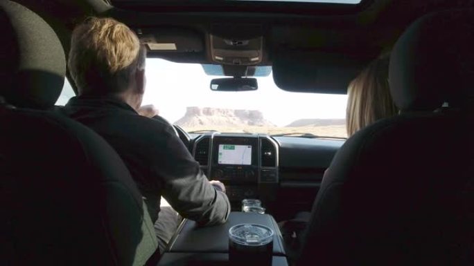 在犹他州马蹄峡谷附近的一个阳光明媚的日子里，中年白人夫妇一起开车跟随地图接近砂岩纪念碑