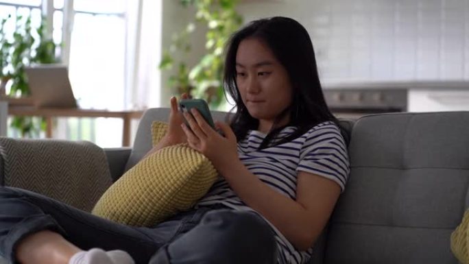 年轻的亚洲妇女拿着手机在社交媒体网站上监视前任