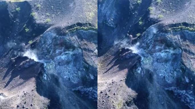 火山火山口冒烟的垂直视频，人们在边缘行走