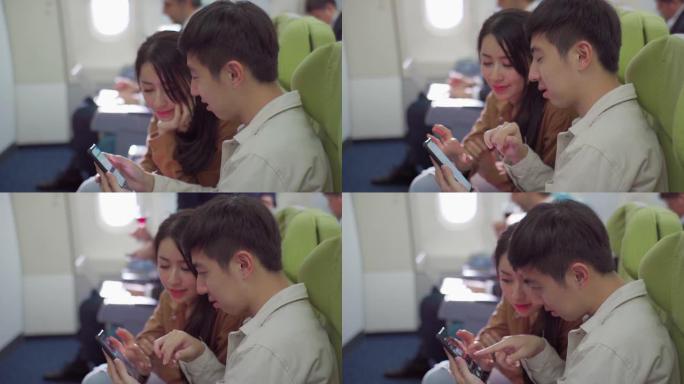 在商用飞机板上，年轻夫妇使用智能手机。