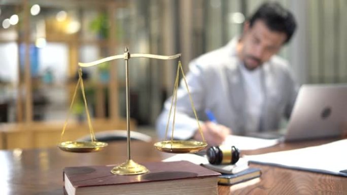 严肃的律师用笔记本电脑工作，在办公室里用带金色天平的木槌记录诉讼。商人强调要有充分的理由。