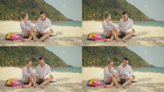 欢快的爱情夫妇在热带沙滩上拿着和吃西瓜片。浪漫的恋人两个人度过夏季周末
