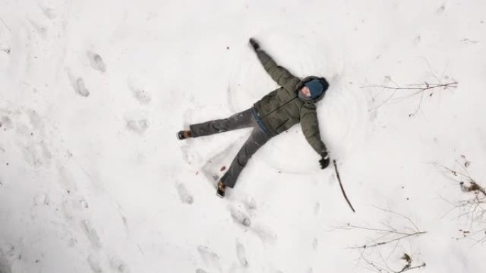 一个喜欢在新鲜雪中制作雪天使的孩子的无人机鸟瞰图