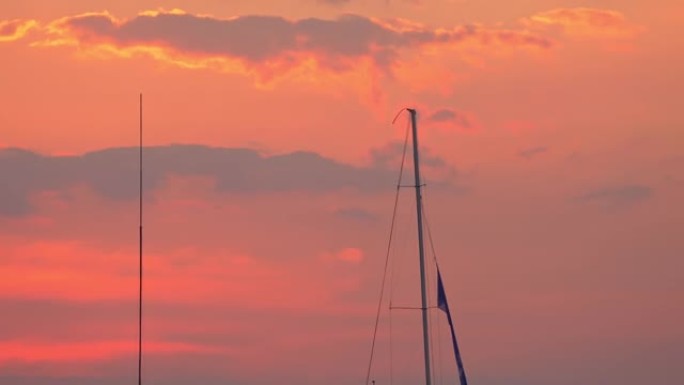 一艘帆船的桅杆在日落天空中的码头上隐约可见