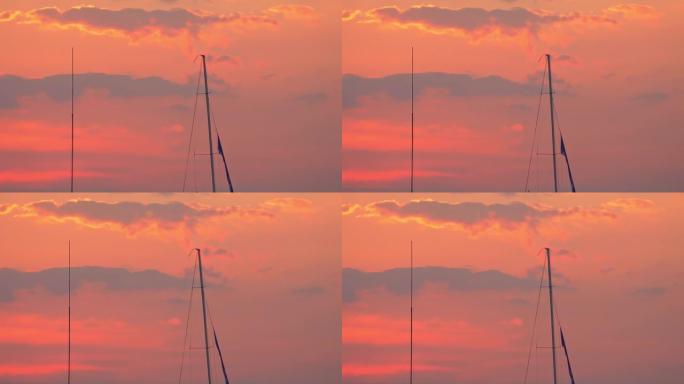 一艘帆船的桅杆在日落天空中的码头上隐约可见