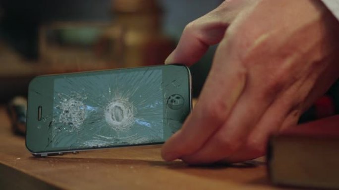 一名男子用锤子砸碎手机屏幕，破坏了科技产品，这是一种数码排毒的视觉标志，也是他想从科技中挣脱出来的渴