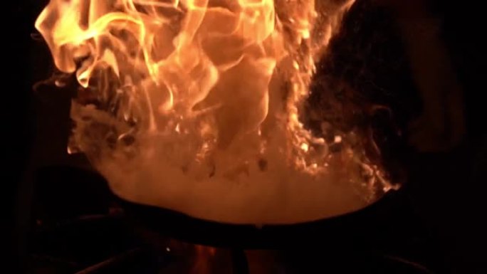 厨师在火上炸香肠和蔬菜，将它们扔在煎锅中。慢动作