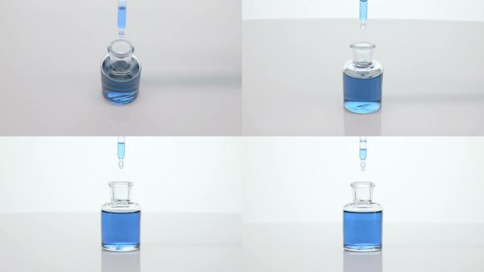 实验室滴管在灰色背景上将蓝色的变色油滴入瓶中