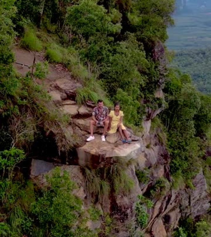 龙冠山泰国甲米，一个年轻的旅行者坐在悬在深渊的岩石上