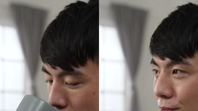 垂直屏幕: 侧视特写轻松的亚洲日本年轻男性在家工作，微笑着茶歇，凝视着远方，在家里的卧室里感到快乐。