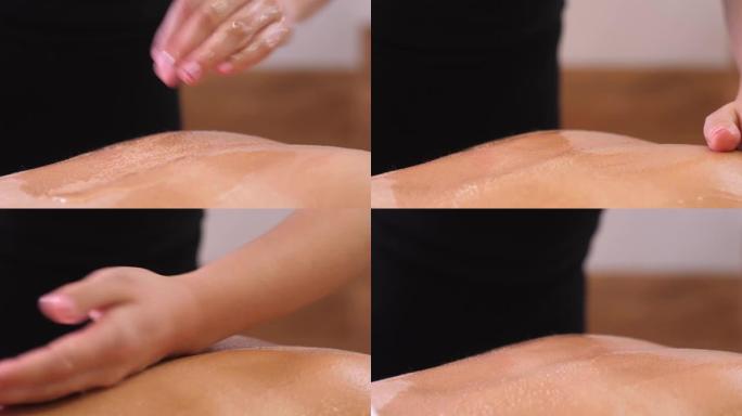 按摩治疗师妇女在放松程序的女性客户的皮肤上倾倒并涂抹油