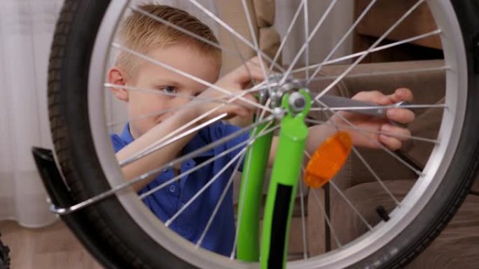 一个八岁的男孩在家里用扳手拧开自行车上的轮子。