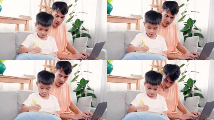 4K，一个亚洲单身父亲正坐在家里客厅的沙发上，教儿子做作业给老师，当时父亲正在自己的笔记本上工作。