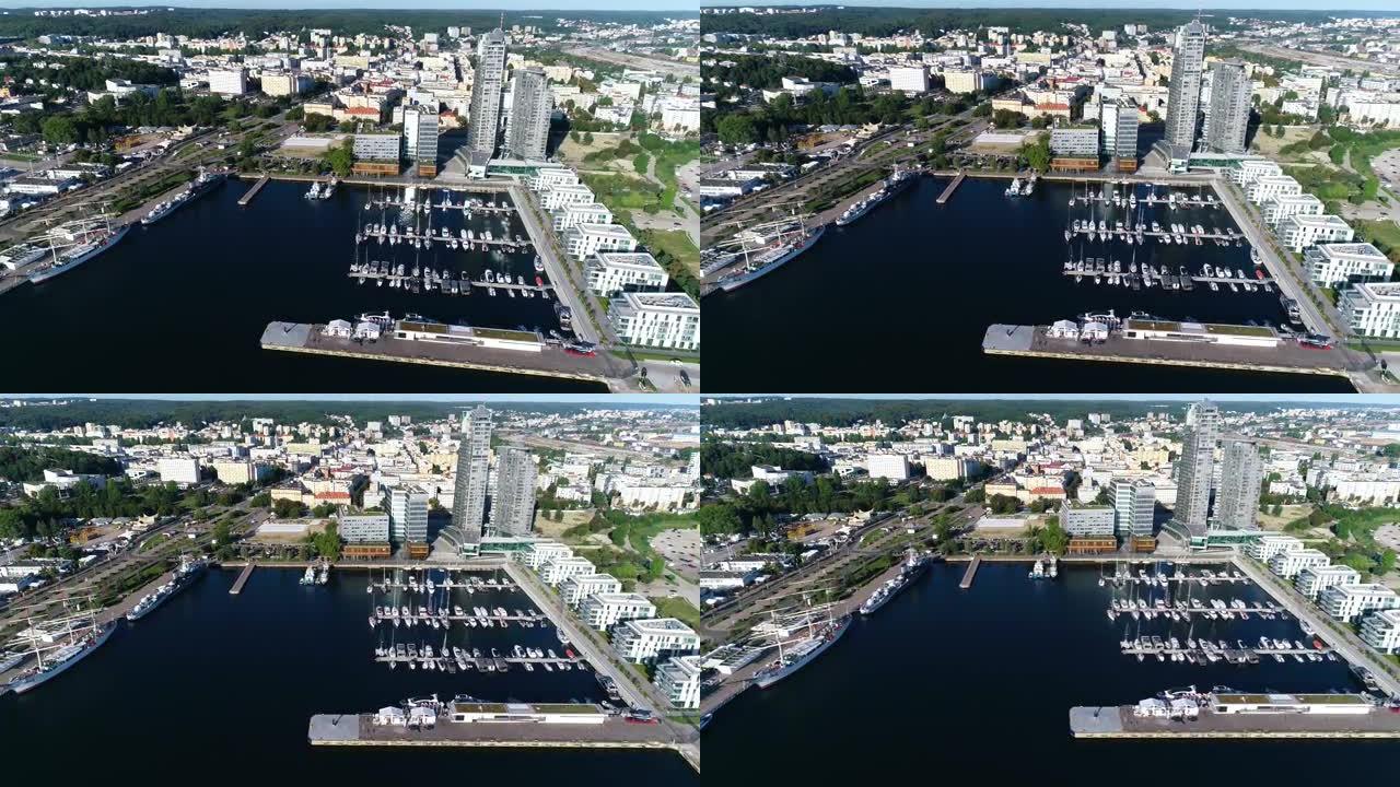 在一个现代化的海滨城市中，满是白色游艇和帆船的港口鸟瞰图。在夏天阳光明媚的日子里，有小船的码头。现代
