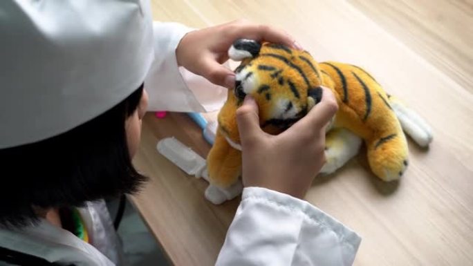一个女孩假装为医生检查老虎玩具眼