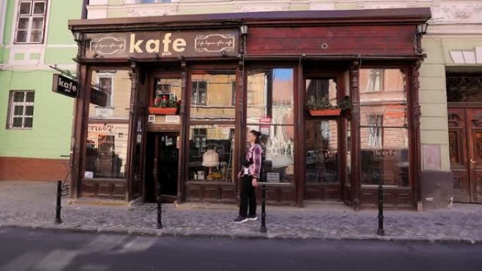一个人走过人行道上的一家复古咖啡馆，环顾四周，一辆汽车驶过