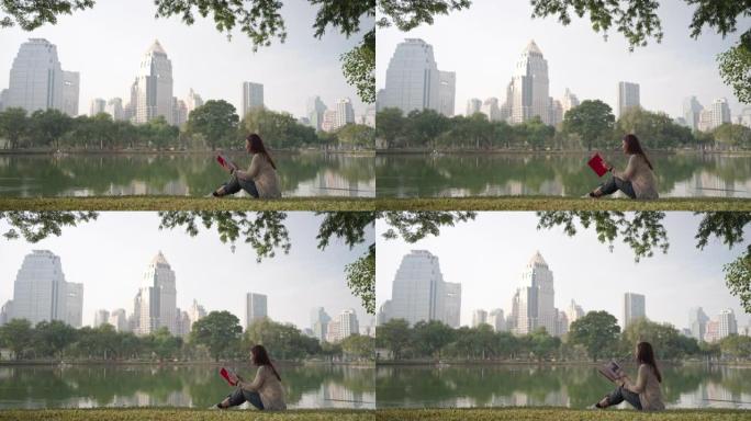亚洲妇女很高兴通过早上在城市公园读书来放松身心，人们在城市自然环境中放松身心。