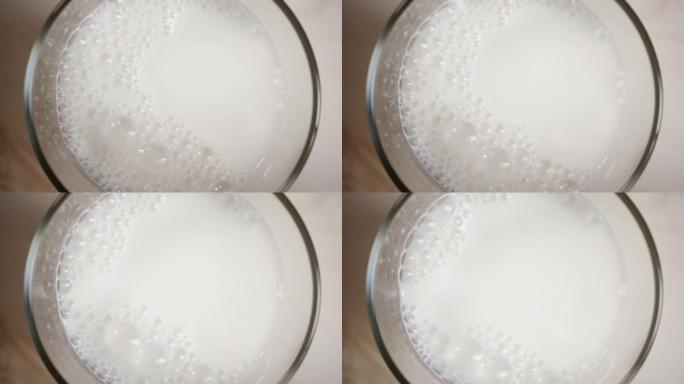 俯视图牛奶倒在木制桌子上的玻璃中，牛奶从透明瓶子中倒出