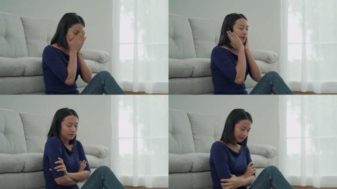 年轻的亚洲女人坐在沙发旁边。女人悲伤、疲倦和担心，或者有精神健康问题。悲伤的女人概念