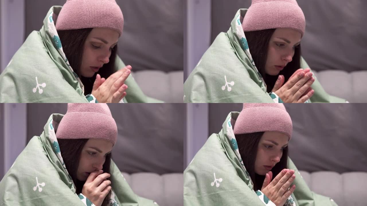 一个戴着毯子的帽子的年轻女子在一个没有暖气的公寓的床上因寒冷而颤抖。由于能源部门的危机，电力和集中供