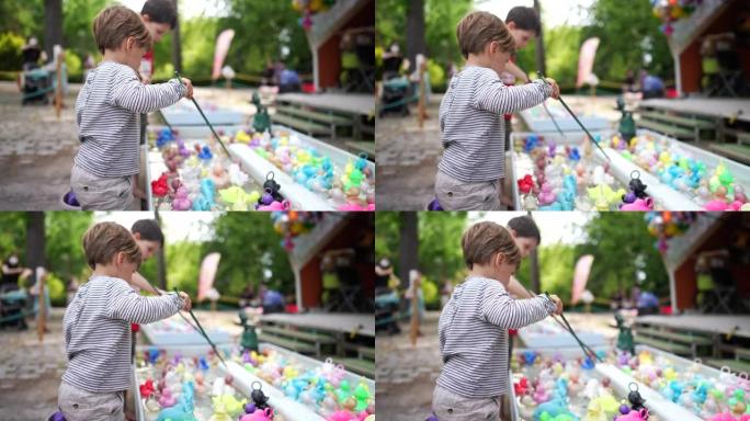 儿童在游乐园游泳池钓鱼塑料鸭子。拿着钓鱼竿钩玩具的孩子