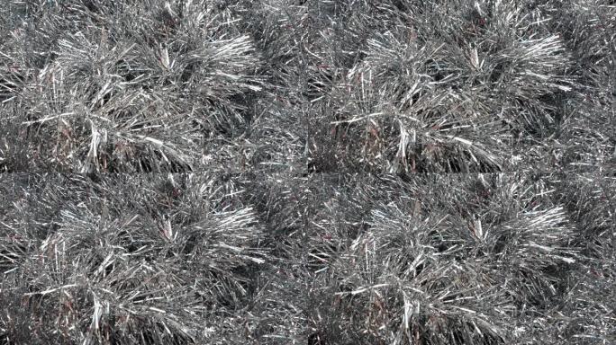 银色明亮的金属丝在风中或选秀中飘扬。圣诞树、室内或冬季街道的圣诞节和新年装饰。空气呼吸下圣诞树针的运