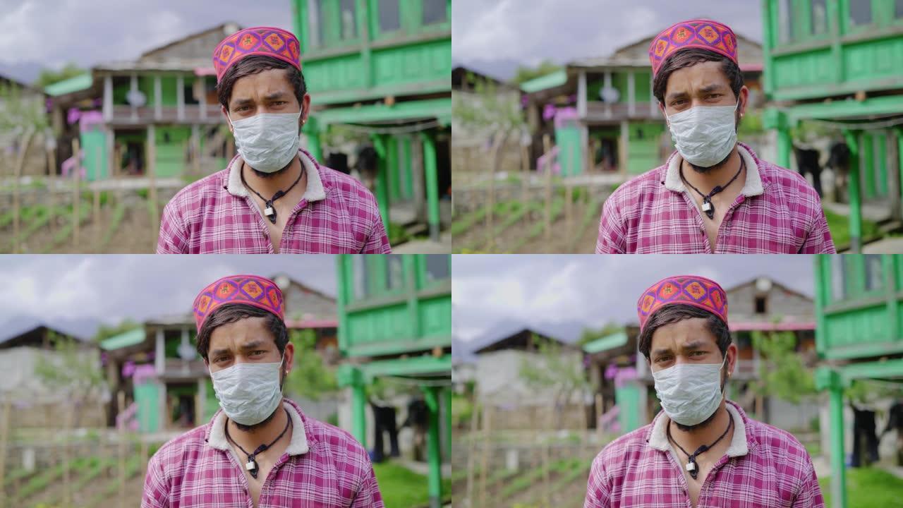 一名年轻的印度男性喜马偕里男子 (Pahadi男性) 的特写镜头，戴着防护面罩，背景是乡村房屋