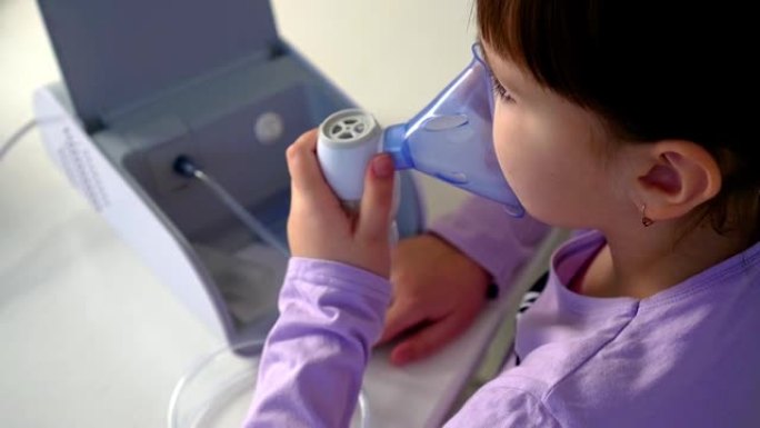 小女孩坐在餐桌旁用医用雾化器吸气