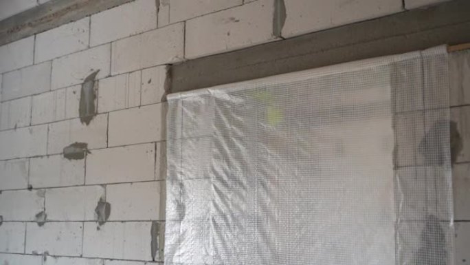 门口用蒸汽屏障密封。由白色加气混凝土砖制成的未完工房屋的裸露墙壁。平稳的摄像机运动