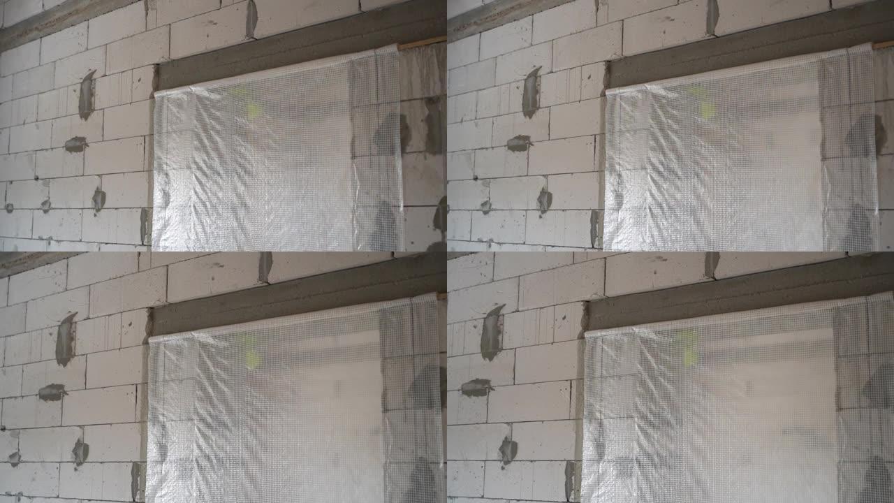 门口用蒸汽屏障密封。由白色加气混凝土砖制成的未完工房屋的裸露墙壁。平稳的摄像机运动