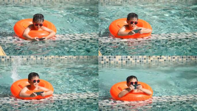 亚洲男孩用智能手机在游泳池玩水下游泳
