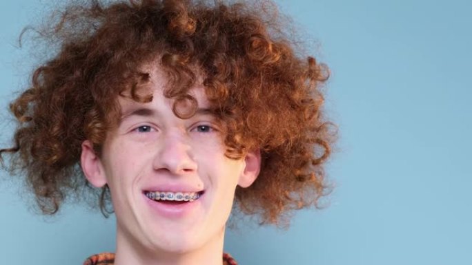 一个笑脸的红发卷发少年的肖像，牙齿上戴着牙套