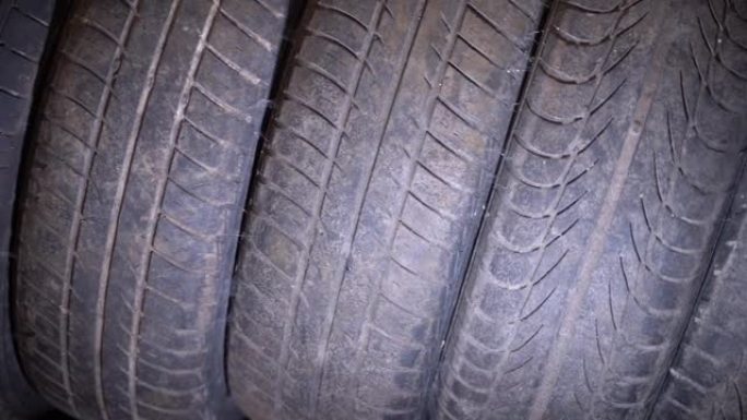 旧磨损的汽车轮胎堆放在仓库特写。平稳的摄像机运动。橡胶上不同的胎面花纹