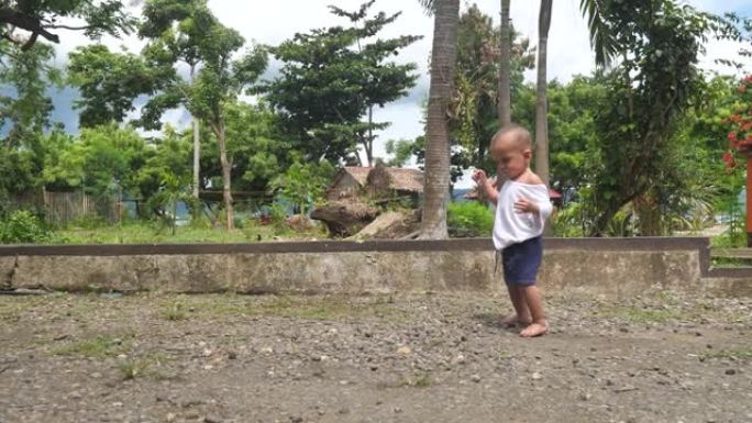 后院的孩子迈出了不确定的第一步，保持平衡，以免摔倒有趣的一岁婴儿步态不确定，想走路并迅速发展，认识到