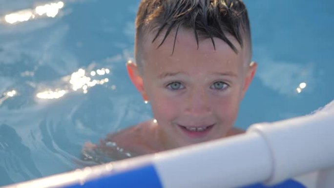 游泳池里的孩子微笑着。暑假期间，儿童男孩肖像对着镜头。