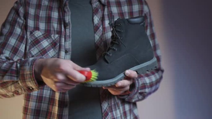 专业护鞋和清洁公司。在涂抹润滑剂之前，男人会从黑色麂皮冬靴上擦去灰尘和灰尘。鞋类维护配件。细心的工人