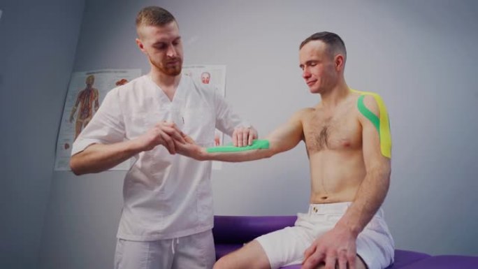运动机能学:理疗师将运动胶带贴在男性身体上。运动员。