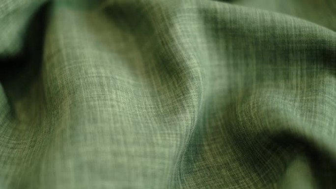 特写镜头视频。绿色亚麻纺织抽象背景。服装行业概念。波浪形材料。丝绒织物线宏。侧视图。特写拍摄素材
