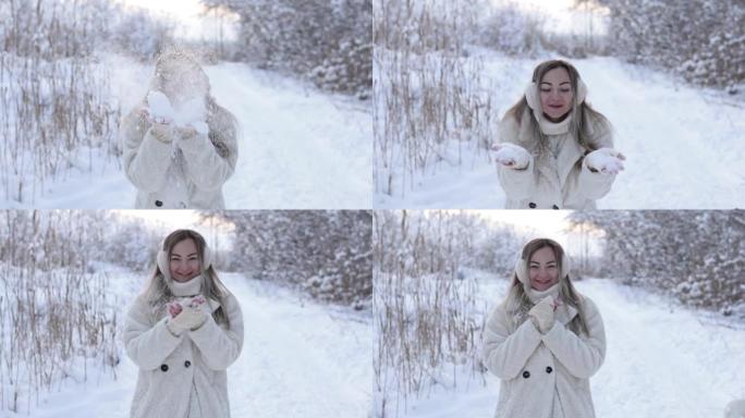 一个穿着冬衣和耳机的美丽女孩以心脏的形式从雪球的手套上吹雪。冬天在森林里放纵雪