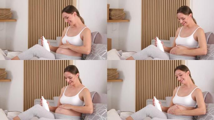 卧室里的孕妇在腹部涂抹护肤品