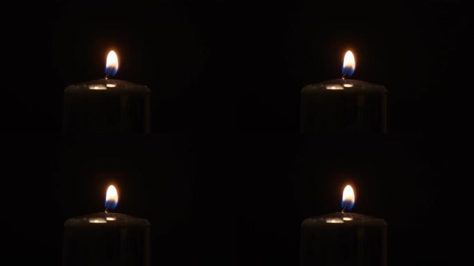 用火柴在黑暗的背景上点燃黑色的石蜡蜡烛。明亮的火焰，火，点火。记忆的概念，仪式，庆典，电力问题，能源