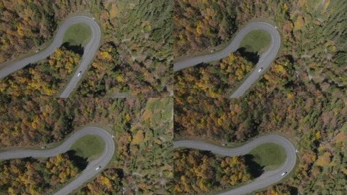 空中无人机在秋天弯曲的山口上拍摄车辆